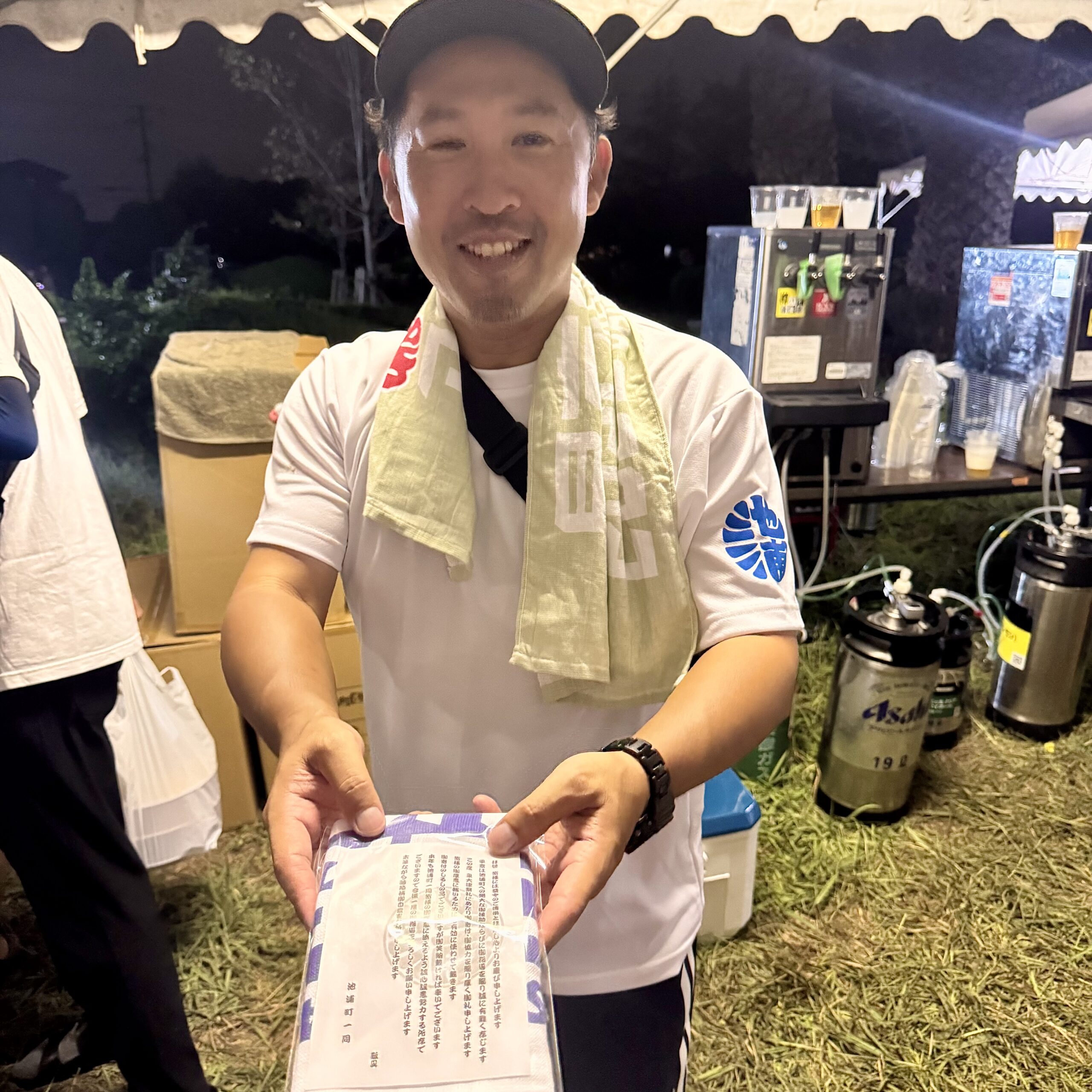 タオルを両手で差し出す。奥にビールサーバー