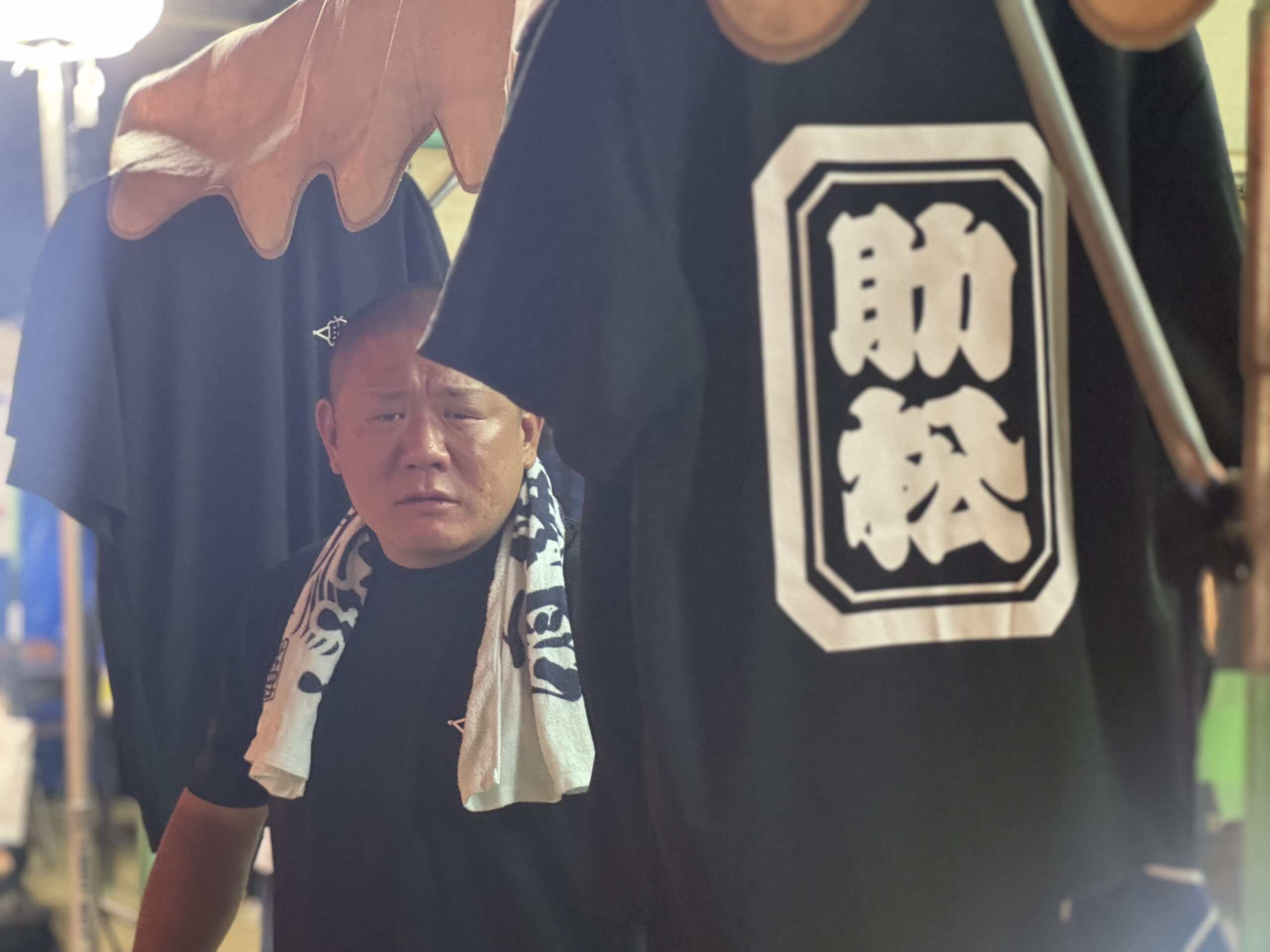 助松の角印が入ったTシャツを掲げる