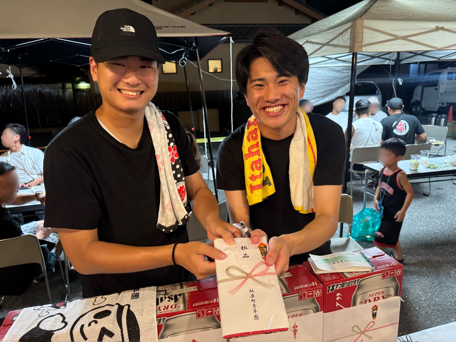 のし紙のかかった包みを持って笑う板原町青年團の二人