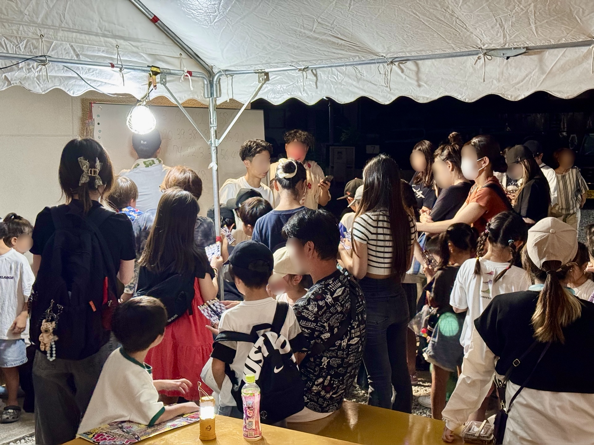 テントの中の人だかり。奥のホワイトボードに番号が並ぶ