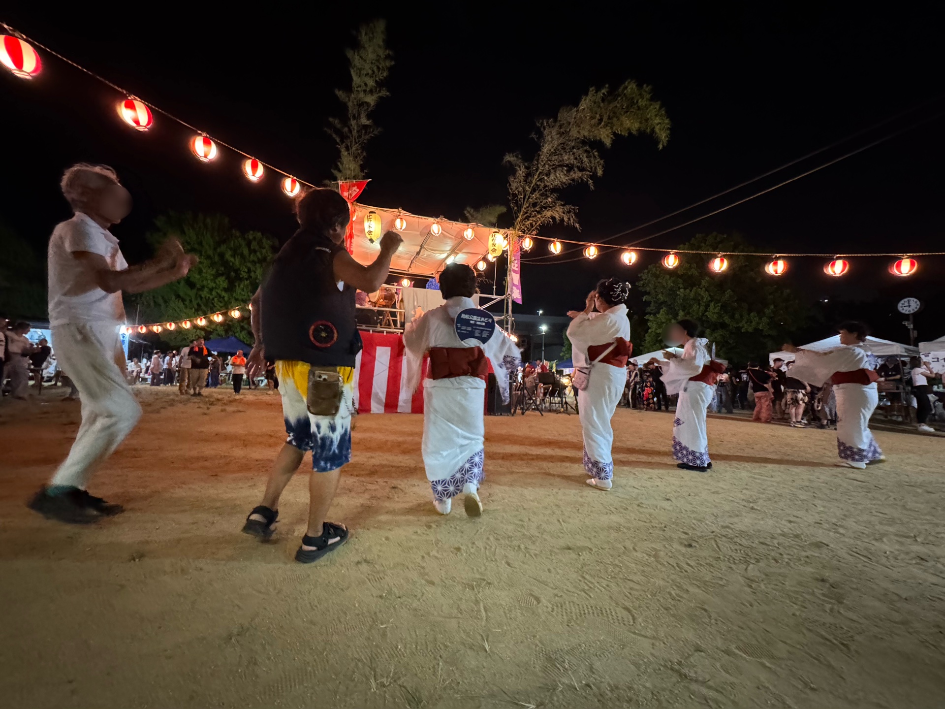 踊りの輪。浴衣の連なりと、櫓、提灯