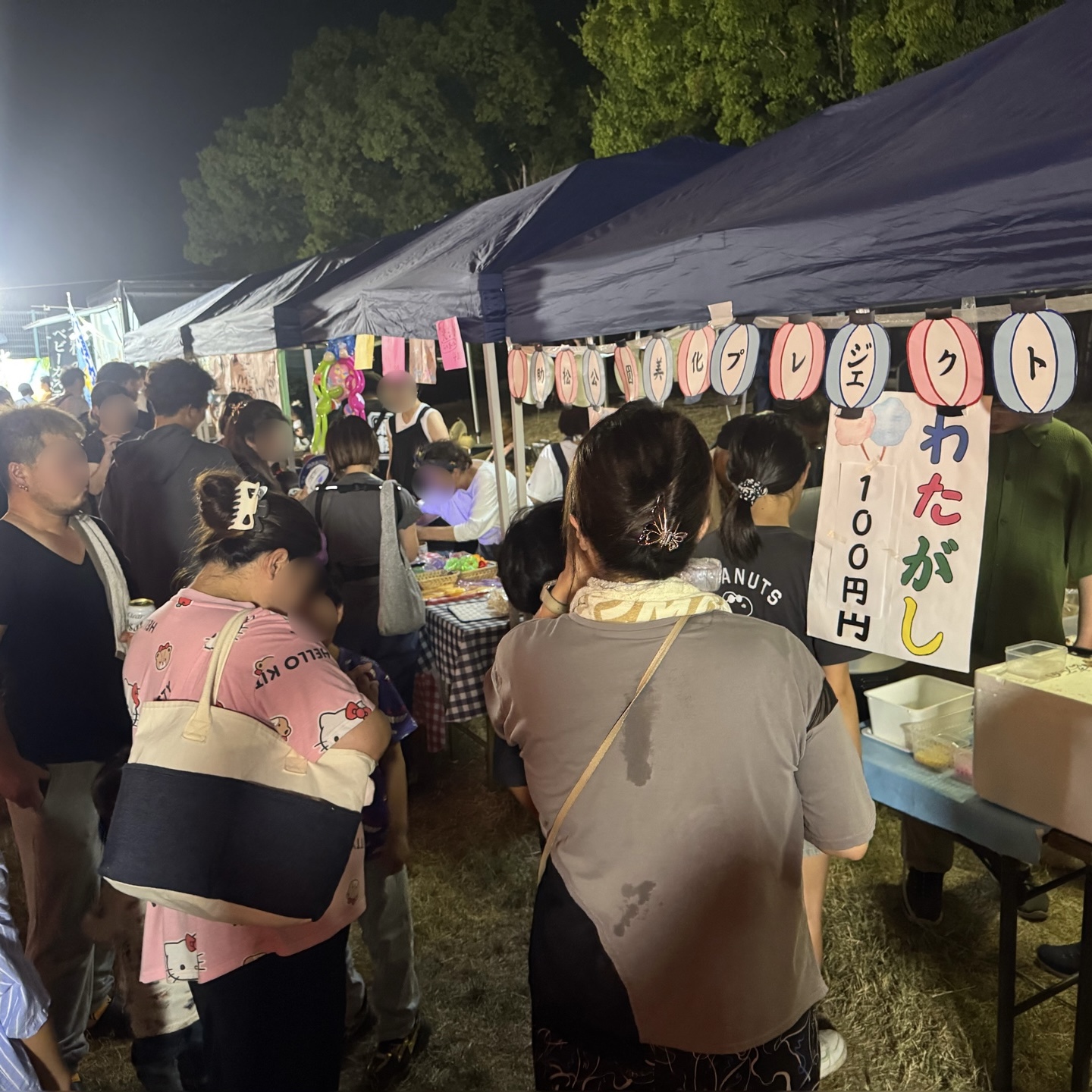 わたがし100円の貼り紙。提灯の列と青いテント